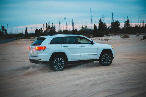 Modern ATV on sandy land behind trees at sundown