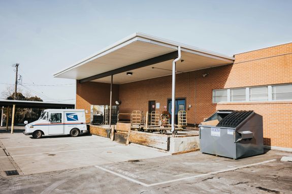 View of a Parking Lot and a Trash Bin at the Back of a Building 