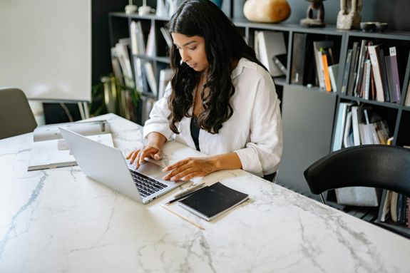 Confident businesswoman working on her laptop in a modern office setting. Perfect for business themes.