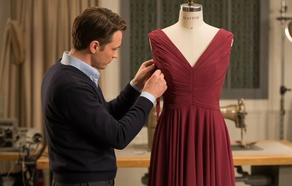 Crop craftswoman in casual wear sitting at old fashioned sewing machine and stitching pieces of fabric while working in workshop