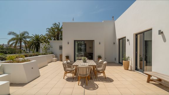 Man in White Robe and White Pants Standing Beside Gray Vacuum Cleaner