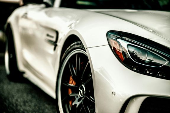 Close-up of a luxury white car highlighting its sleek design and headlight. Ideal for automotive enthusiasts.