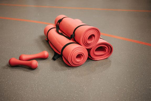 Rolled Yoga Mats Beside a Pair of Red Dumbbells