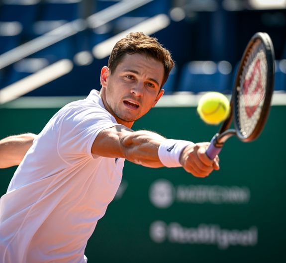 Tennis player standing with racket and ball