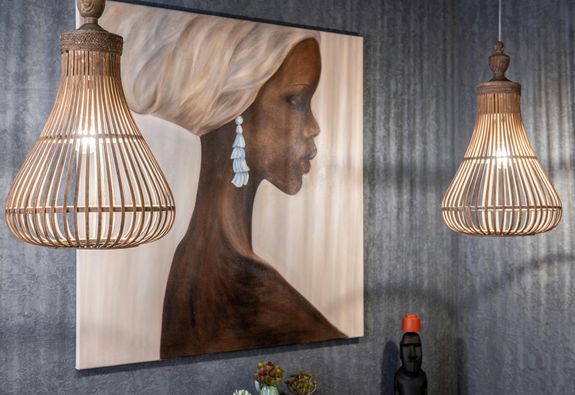 Painting of African woman on wall between shiny lamps