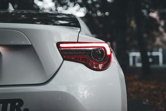 Detailed view of a white car's tail light in a moody outdoor setting.