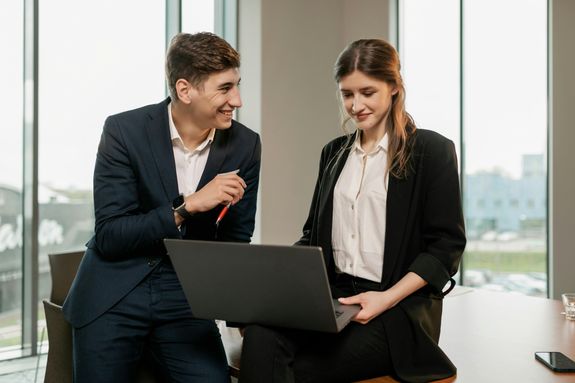 Business professionals discussing ideas while working on laptop in a bright office.