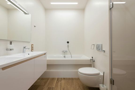 Bathtub and shower cabin in light bathroom with white furniture and tiled walls