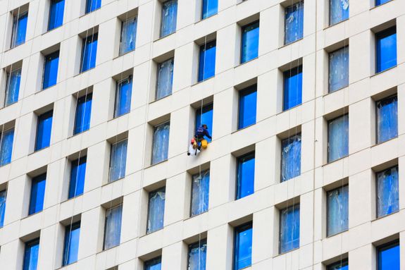 Man Working at Height Cleaning the Windows in a Skyscraper