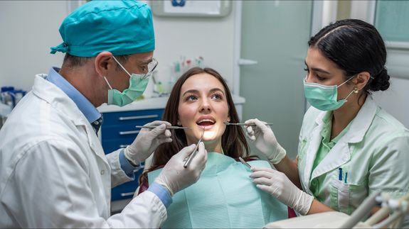 A Person Wearing Blue Latex Gloves Holding a Mirror in a Woman's Mouth
