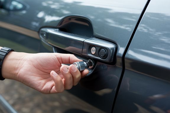 Hands of a Man Unlocking Car Trunk with a Key
