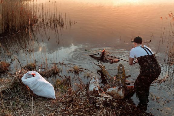 A Man Scooping Trash in a Lake
