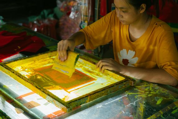 A woman is working on a screen printing machine