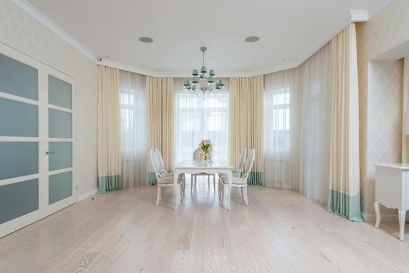 Dining table with chairs in room near windows with curtains