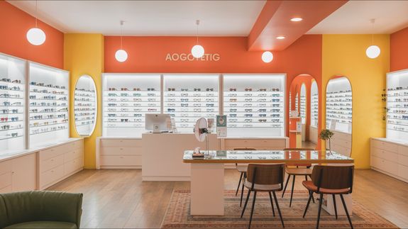 Crop anonymous female optometrist wearing medical robe holding modern trial frame with lenses in hands in modern optometry clinic