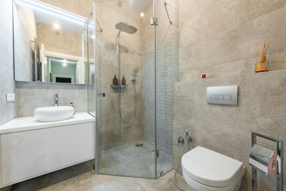 Contemporary bathroom featuring a glass shower, beige tiles, and stylish fixtures for a modern aesthetic.