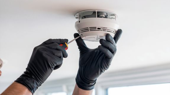 A man on a ladder cleaning air conditioners on a wall
