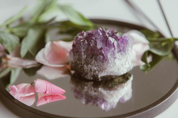 A Purple Gemstone on a Mirror with Pink Flower Petals