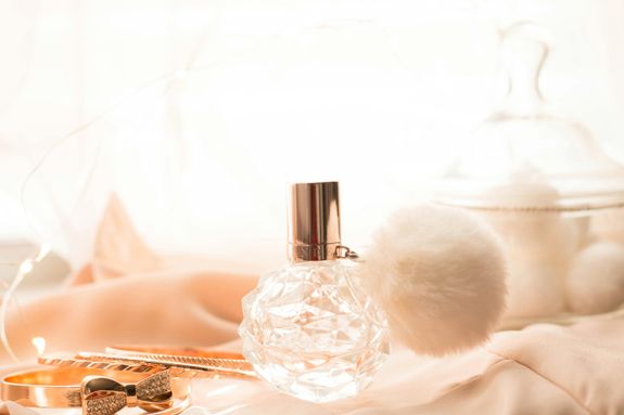 Bottle of Perfume and Golden Accessories Lying on Pink Fabric 