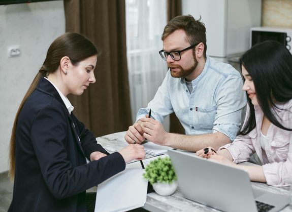 A couple discusses financial documents with their advisor, highlighting investment strategies.