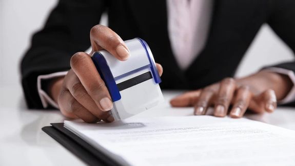 Businesswoman using phone in modern office with laptop and documents.