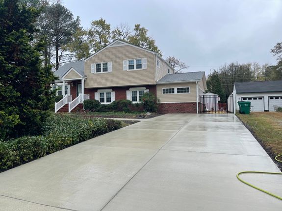 Man in Orange Jacket and Pants Standing on Road Using a Power Spray