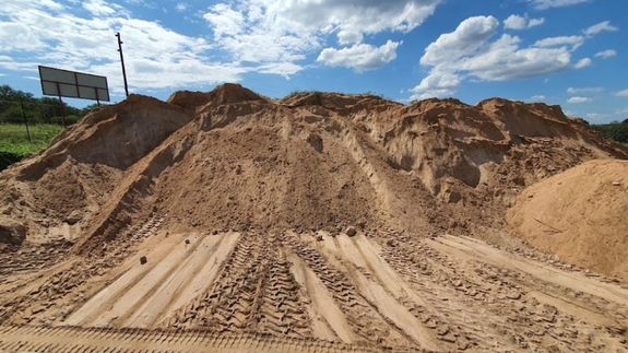 Man in Black Shirt Holding Gray and Orange Wheelbarrow