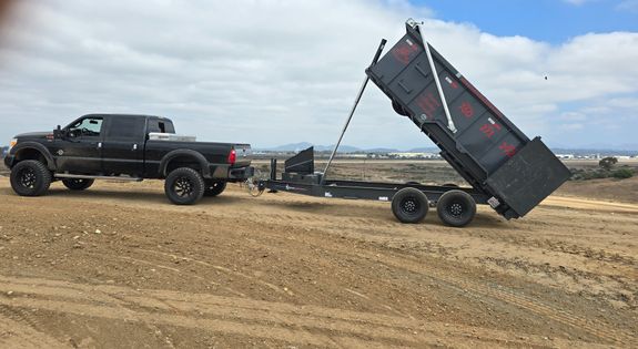 Unrecognizable workmen standing near pile of metal scrap in dump