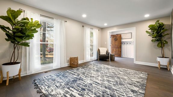 African American woman cleaning a table with orange gloves in a cozy, modern living room setting.