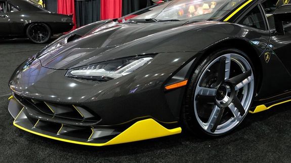 Detailed view of a sleek red sports car headlight with water droplets enhancing its glossy finish.