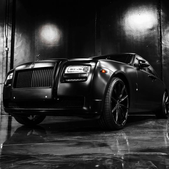 Detailed view of a sleek red sports car headlight with water droplets enhancing its glossy finish.