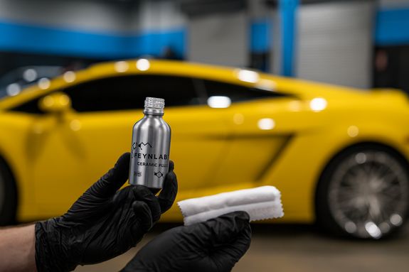 Detailed view of a sleek red sports car headlight with water droplets enhancing its glossy finish.
