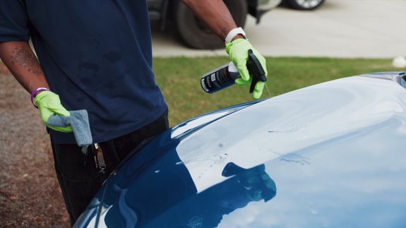 Detailed view of a sleek black car's taillight with red illumination, reflecting dusk light.
