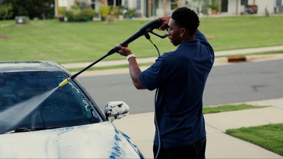 Worker applying a car wrap using a heat gun for precise adhesion.