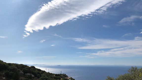 Crop unrecognizable coworkers in formal wear standing at table with laptop and documents while greeting each other before meeting