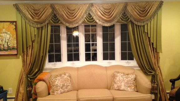 Side view of smiling florist with long dark hair in apron standing near counter and smelling flowers in vases in cozy floristry studio
