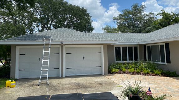 Man in Orange Jacket and Pants Standing on Road Using a Power Spray