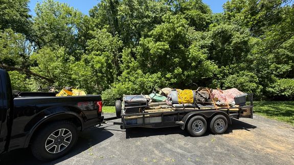 A close-up photograph of a black plastic garbage bag against a plain concrete wall, highlighting waste management.