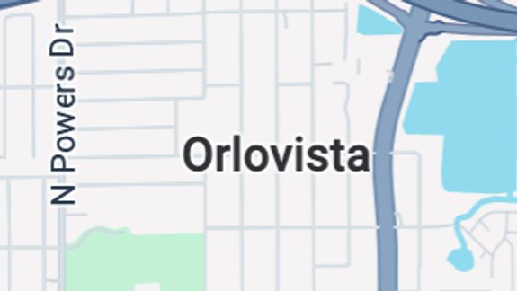 Detailed view of a sleek red sports car headlight with water droplets enhancing its glossy finish.