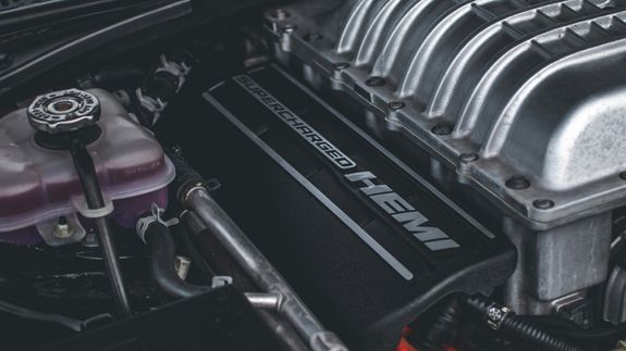 Detailed view of a sleek black car's taillight with red illumination, reflecting dusk light.